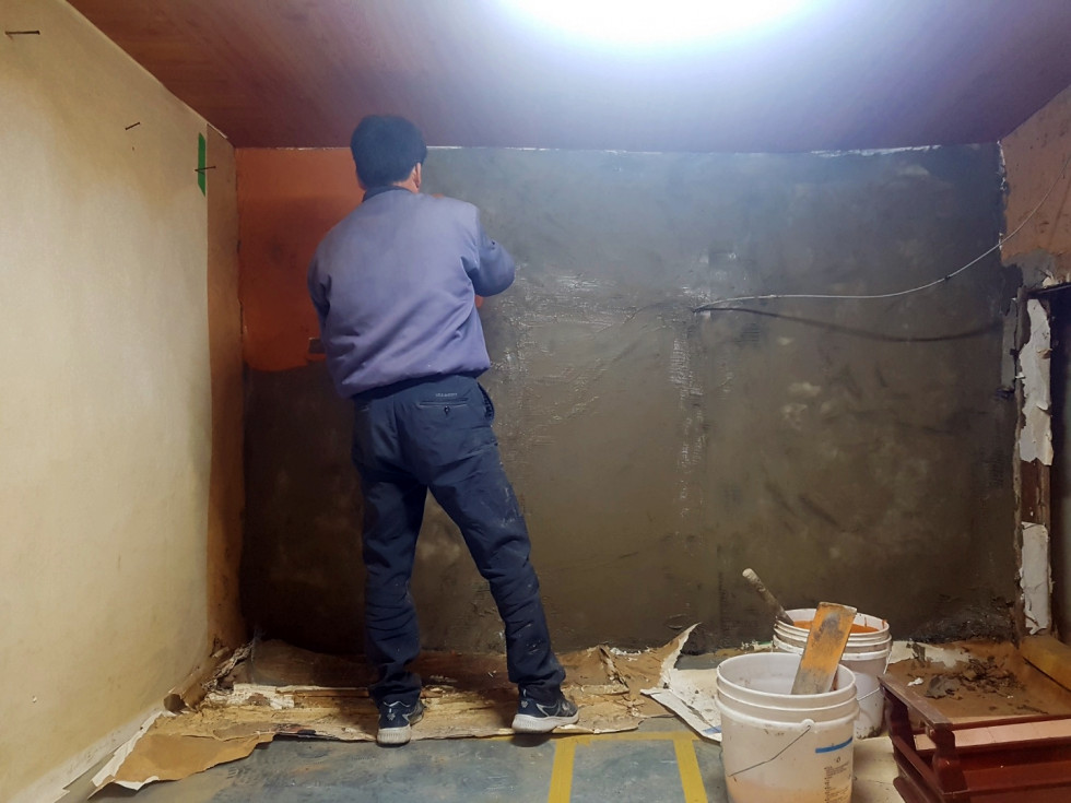 방안 벽에 시멘트로 보수공사를 하는 모습입니다.